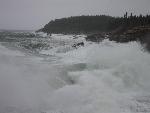 Big waves crash against the rocky shore.