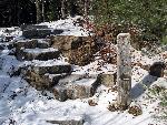 Trail and signpost covered in snow.