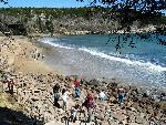 People explore rocky/sandy beach.