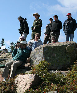Park ranger stands with other people on rocks.