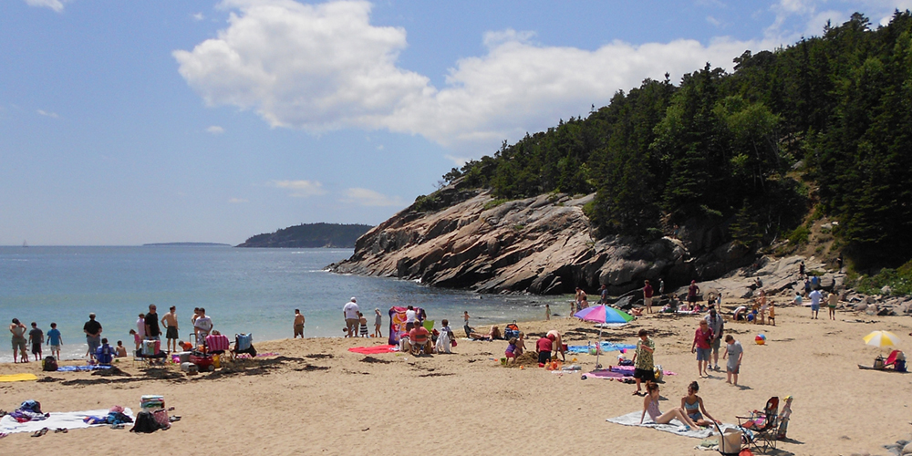 Swimmers and sunbathers enjoy Sand Beach on a bright, sunny day.
