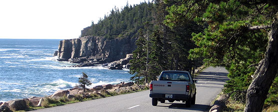 Pickup truck drives along shoreline.