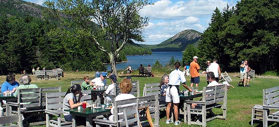Visitors eating on the lawn overlooking Jordan Pond