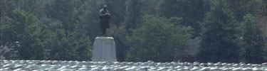 Bronze figure of the Minnesota Monument rises over the top of white gravestones