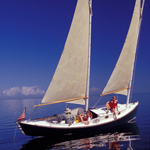 Three people in a sailboat on calm seas