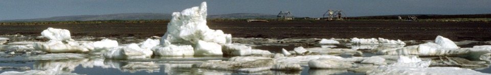 Chunks of melting sea ice along a shoreline and subsistence camps on the beach in the background.