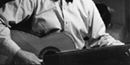black and white photo of Carl Sandburg playing one of his many guitars black and white photo of Carl Sandburg playing one of his many guitars