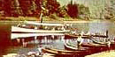 A small steamboat passing a beach with rowboats A small steamboat passing a beach with rowboats
