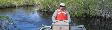Researcher in Boat Among Mangroves