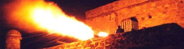 The night sky is set ablaze by the muzzle flash of a Spanish cannon.