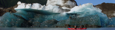 Kayakers in front of large iceberg