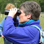 A women with binoculars looks for birds