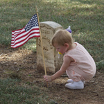 Small child placing a flag in front of a Civil War headstone in the National Cemetery