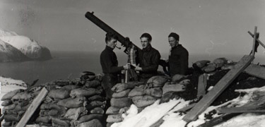 Three soldiers at Fort Schwatka, Amaknak Island, near Dutch Harbor with a 50 caliber antiaircraft gun.