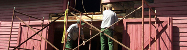park maintenance workers preserving a historic barn structure