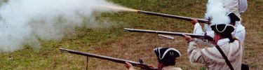 The air is thick with gunpowder smoke as the British soldiers fire their flintlock muskets.