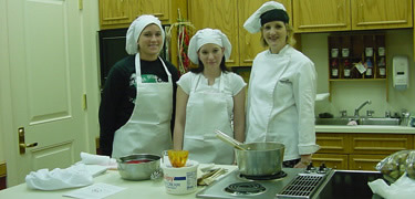 Three cooks at the stove demonstrate Cajun cooking in the kitchen of the Prairie Acadian Cultural Center.