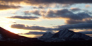 Setting sun casts dramatic highlights and shadows on the clouds and snow covered mountains. Setting sun casts dramatic highlights and shadows on the clouds and snow covered mountains.