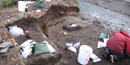 An archeologist excavates a house pit overlooking a stream. An archeologist excavates a house pit overlooking a stream.