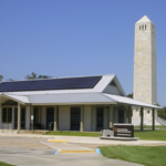 Image is low building with tall white monument behind it