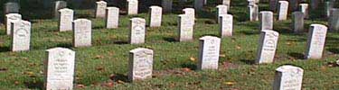 The white gravestones of Chalmette National Cemetery stand in rows on the green grass.