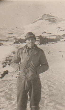 A man in uniform stands in the snow