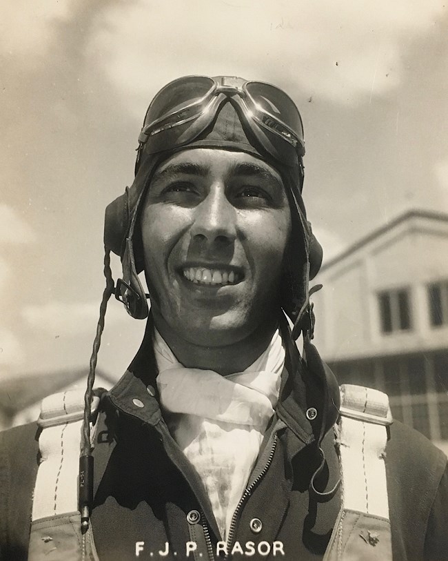 Sepia-toned portrait of man with flight goggles on head.
