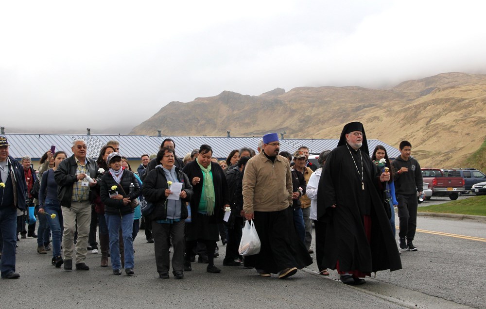 Group of people led by a bishop in front of mountains