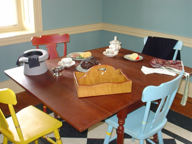 Photo of a table set as if travelers had just left. All items reproduction.