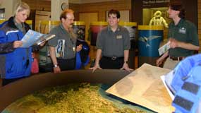 A picture of an interpreter speaking to people at the round Alaskan map in the Anchorage location.