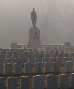 Stone monument topped by brozne statute of a young soldier.