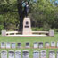 Stone and bronze monument with headstones in front of it