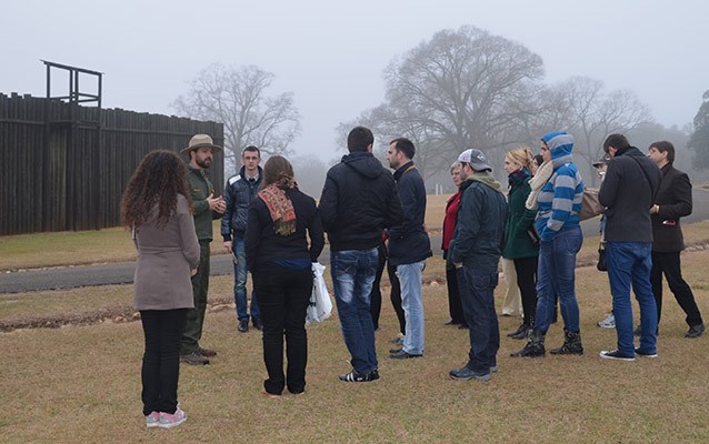 Park ranger leads college students in a discussion in front of the stockade wall