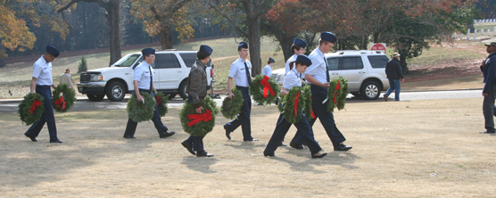 Young men in uniform carrying Christmas Wreaths