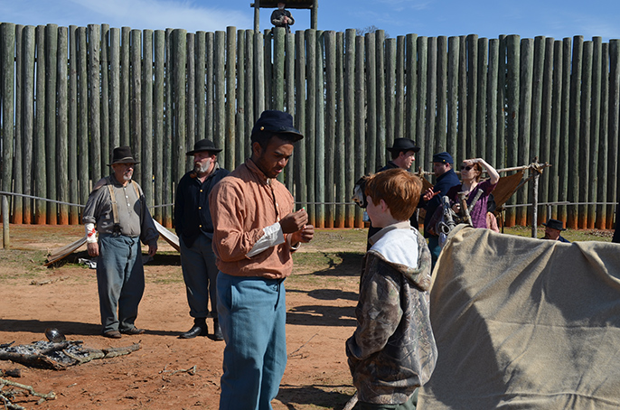 living historians dressed as prisoners interact with visitors.