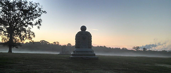An autumn sun rises over monuments.