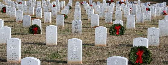 Holiday wreaths decorate rows of white headstones