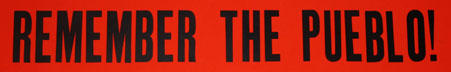 Red bumper sticker with the words, "Remember the Pueblo"