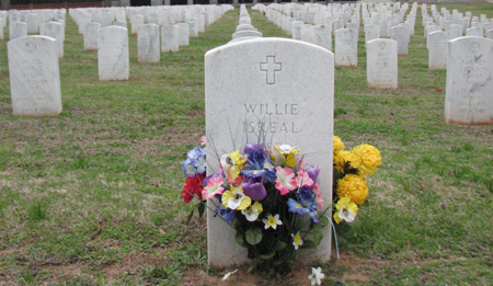Artificial flowers in front of a white headstone