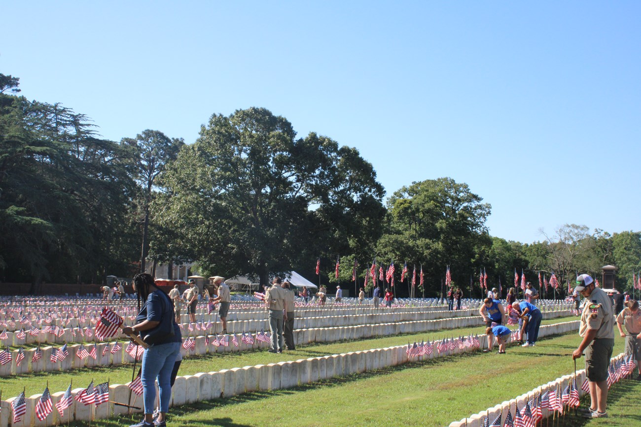 Volunteers placing American flags on headstones