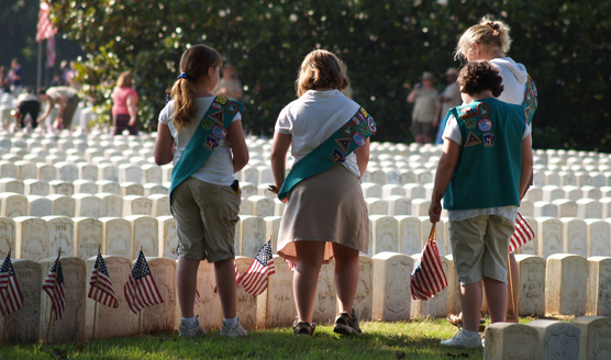 A group of Girl Scouts place flags on graves in the Andersonville National Cemetery.