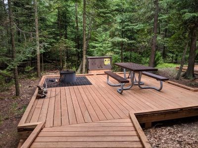 Forested camping area with wooden boardwalk.