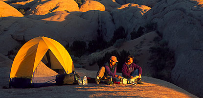 Backpackers prepare a meal as the sun sets.