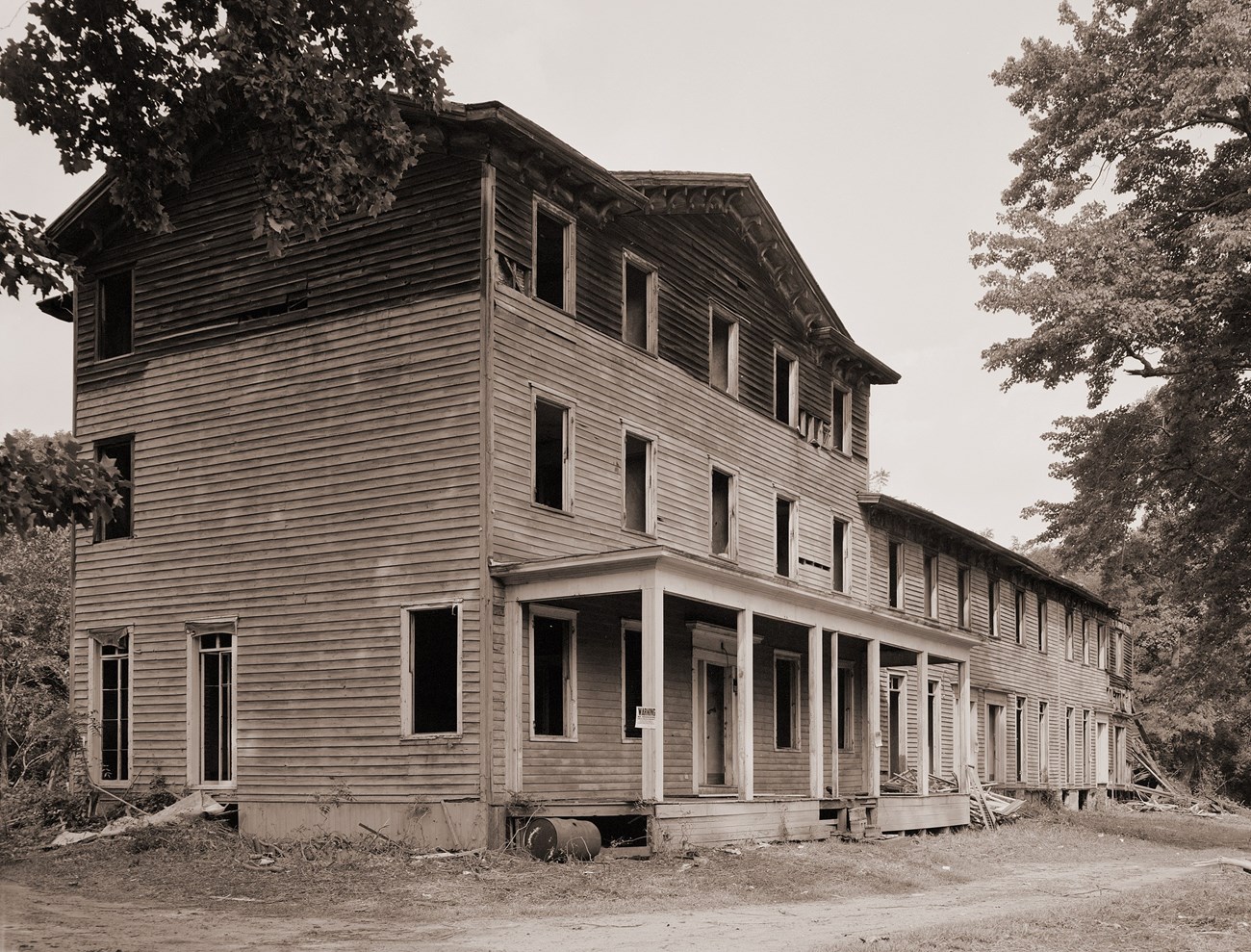 North American Phalanx main housing, photographed before demolition. Three story building with wooden siding and all windows broken and without glass and a two story extension attatched to the right side