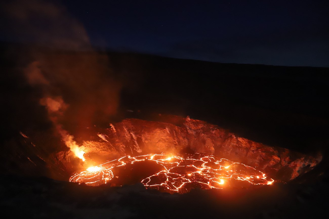 photo of a glowing lava lake taken at night