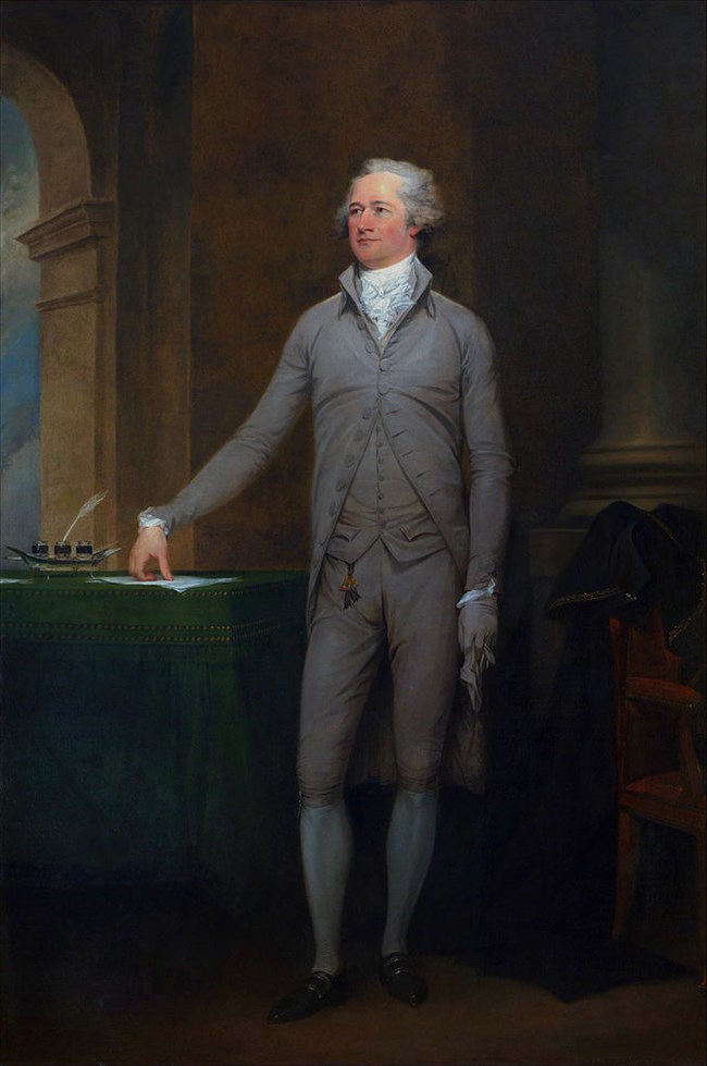 A painting of Alexander Hamilton, who stands next to a table, and with one arm, rests his right hand upon papers on the table.