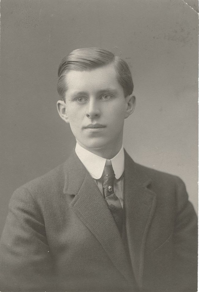 Joseph P. Kennedy sits for a portrait. 1913. Dark suit with tie and pin. Large white color on shirt.