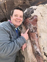 Photo author portrait woman in gray jacket pointing at a fossil.