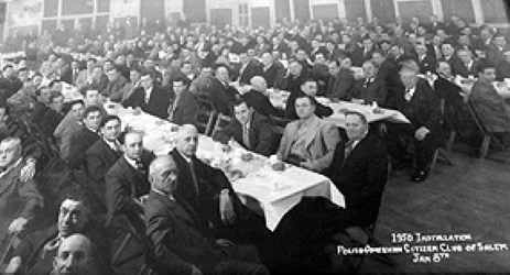 Rows of men sitting at tables at a formal banquet.