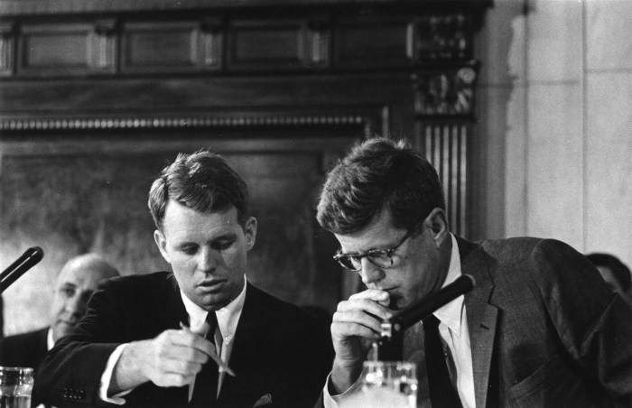 A black and white photo of RFK and JFK looking down and studying a document.
